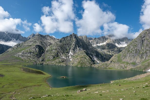 Krishansar Lake near Sonamarg, Kashmir: a deep blue alpine lake below grey peaks with patches of snow, green meadows in the foreground